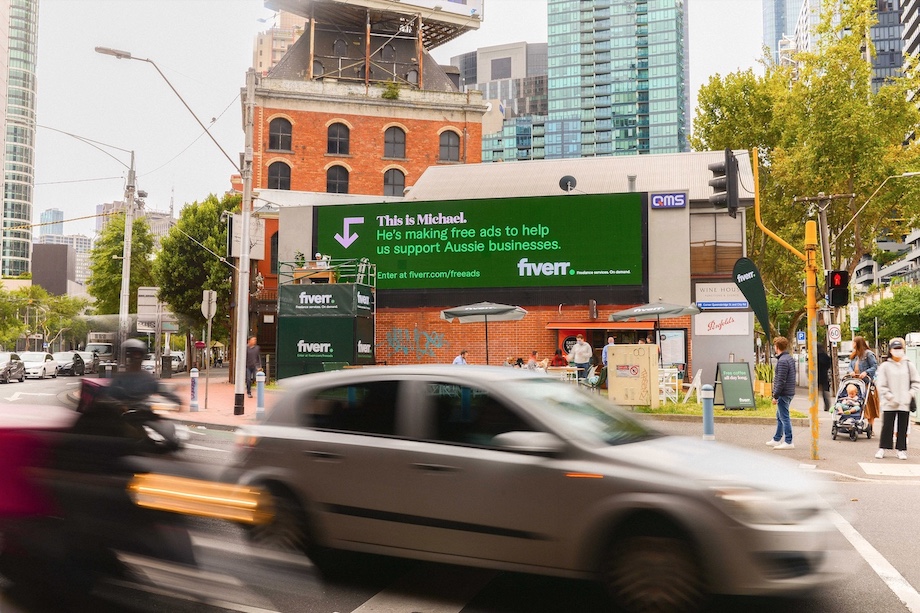 A freelancer attached to a large format billboard makes ads for Aussie businesses in new world-first Fiverr campaign via By All Means